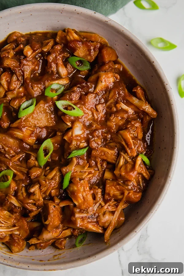 A serving bowl filled with BBQ jackfruit topped with green onions.