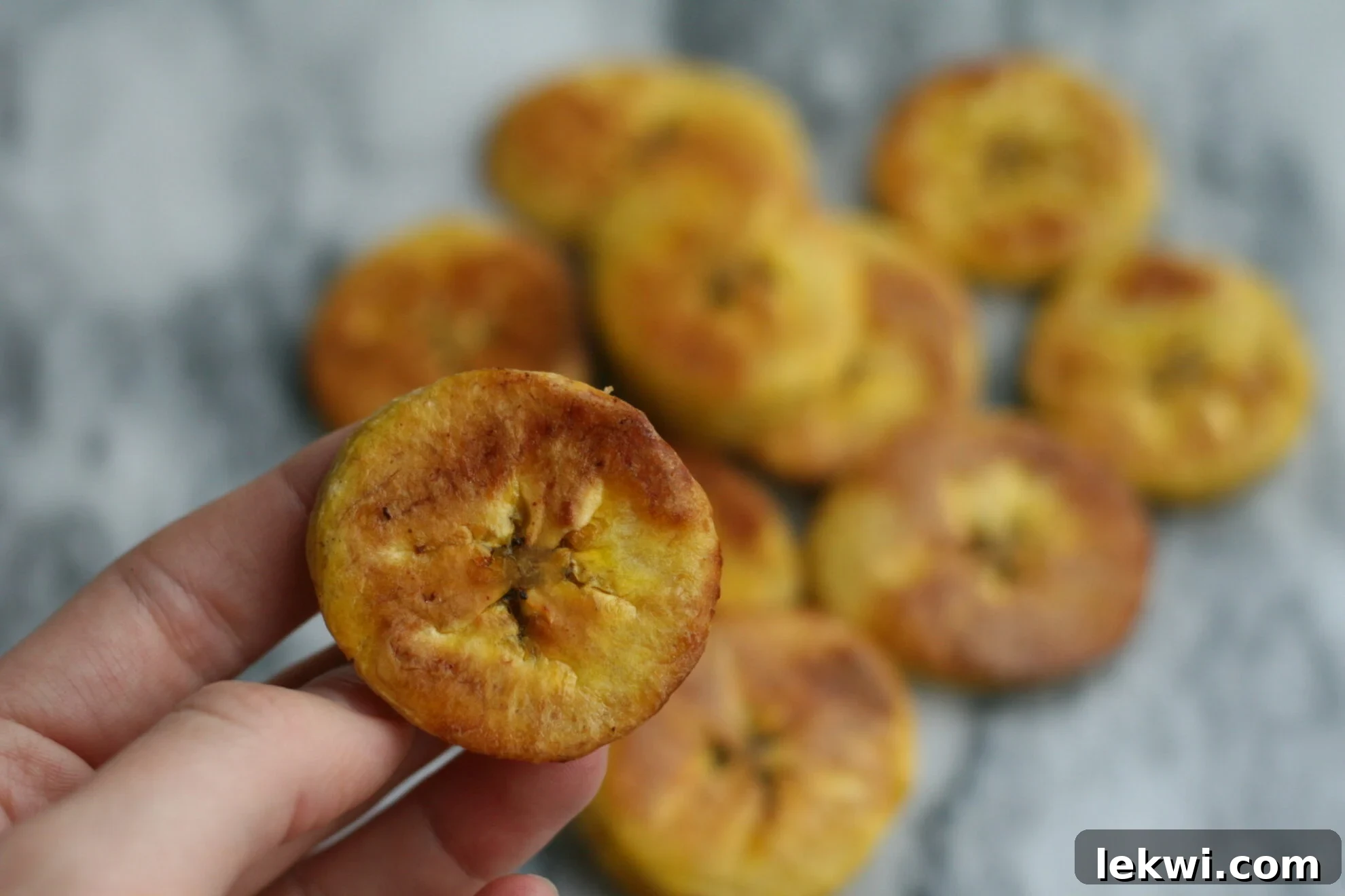 Green plantains and a jar of ghee on a wooden surface.