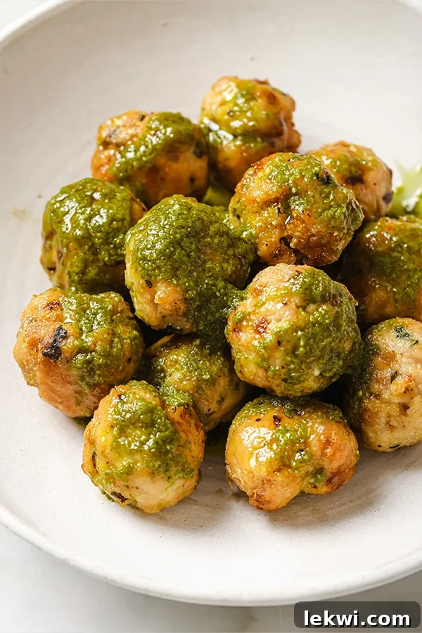 Delicious turkey pesto meatballs served with fresh pesto on a plate.
