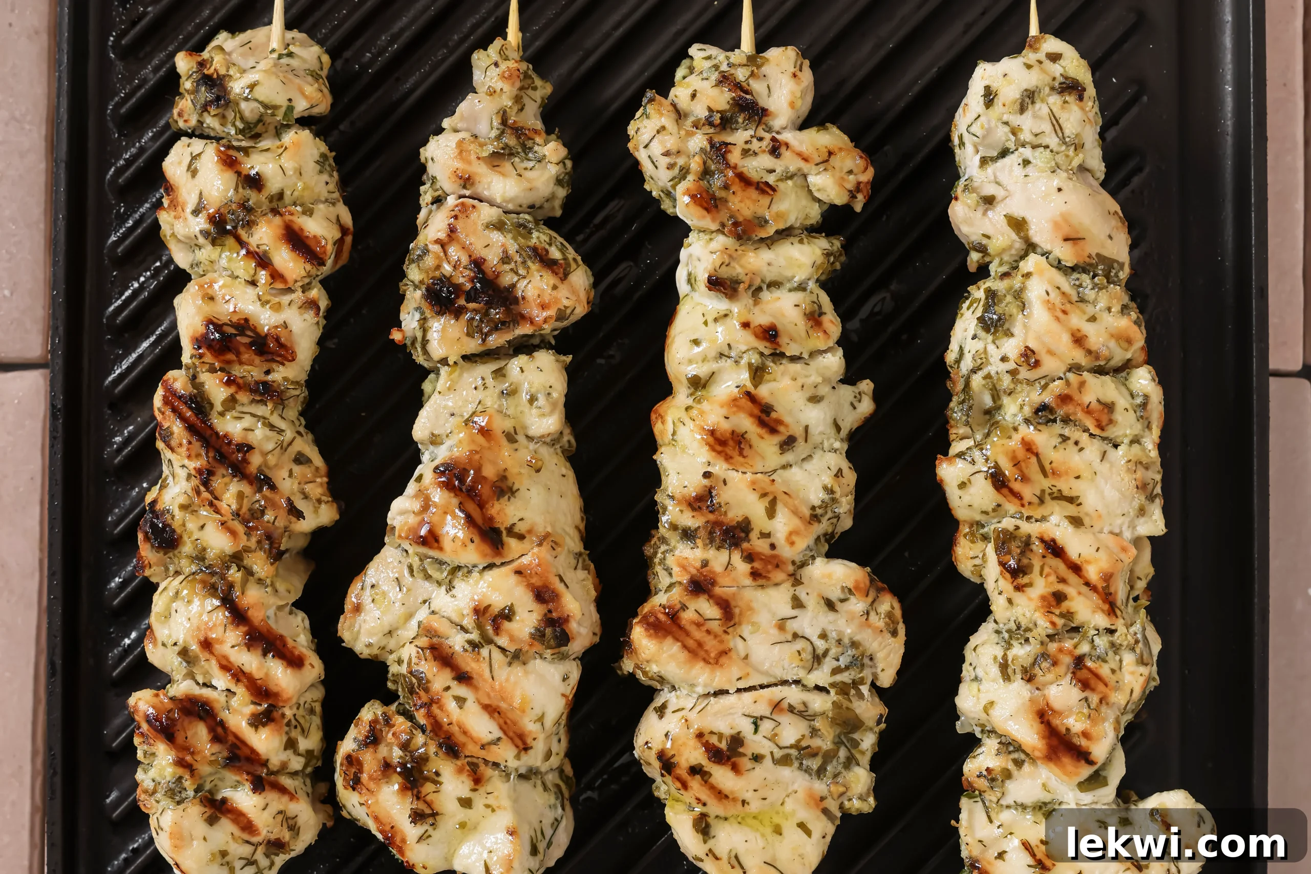 Chicken souvlaki skewers cooking on an indoor grill pan.