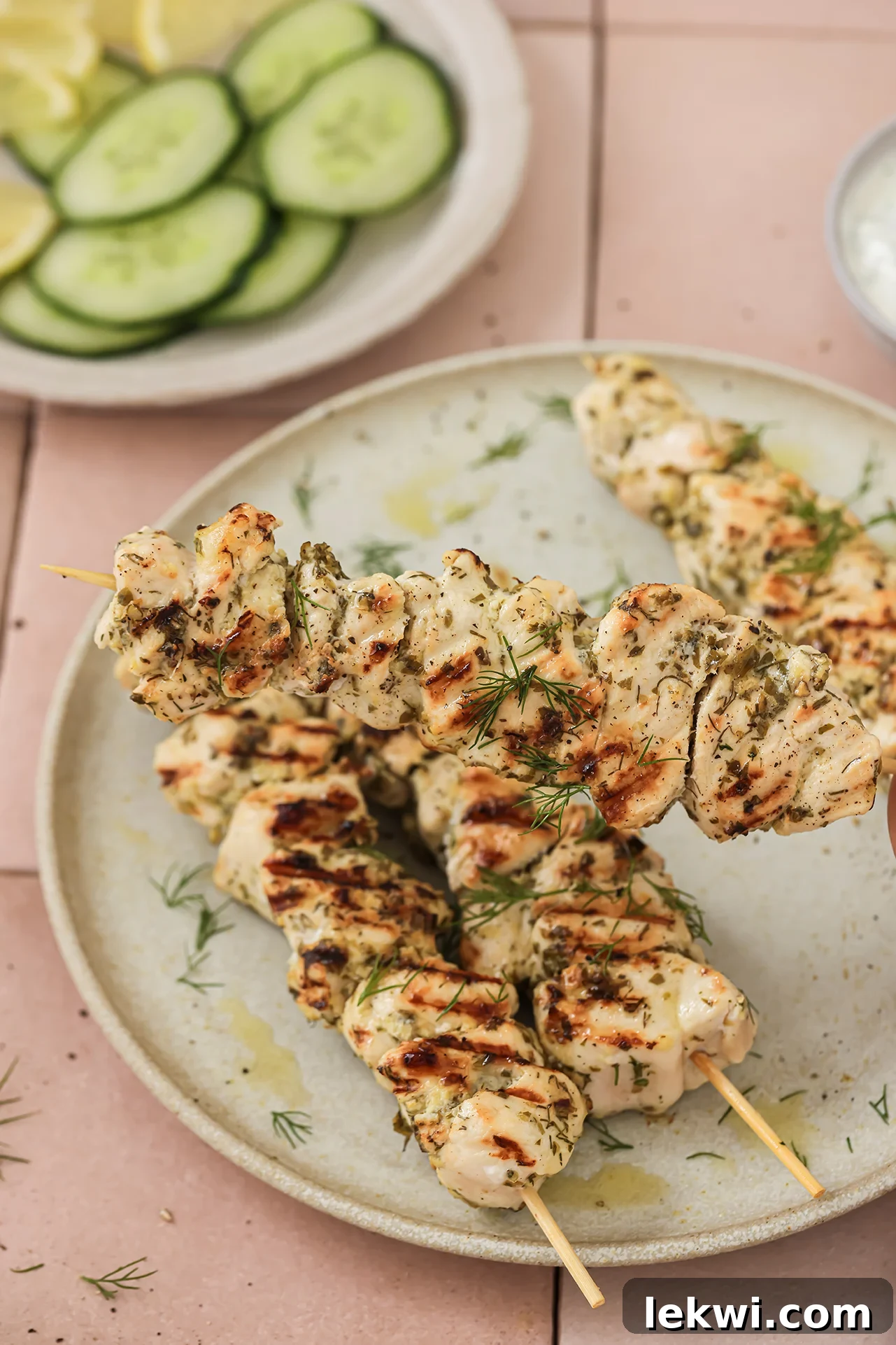 Chicken souvlaki on a plate, with one skewer being lifted.