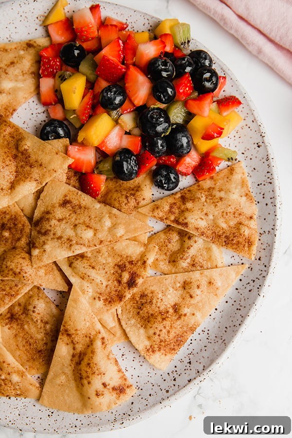 A beautifully arranged speckled plate featuring golden-brown grain-free cinnamon sugar chips paired with a colorful medley of fresh fruit salsa, highlighting the inviting texture of the chips.