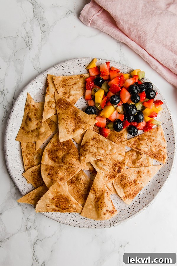 A close-up shot of crispy cinnamon sugar chips perfectly nestled beside a vibrant bowl of fresh fruit salsa, showcasing the appealing textures and colors of this delightful snack.