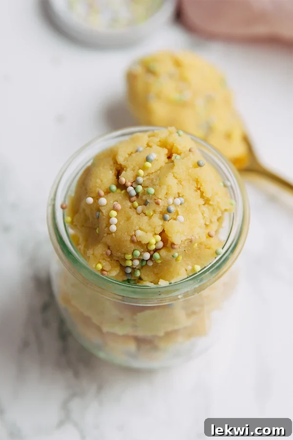 A beautiful glass jar filled with vibrant, edible cake batter, garnished with colorful sprinkles, promising a delightful and safe indulgence.
