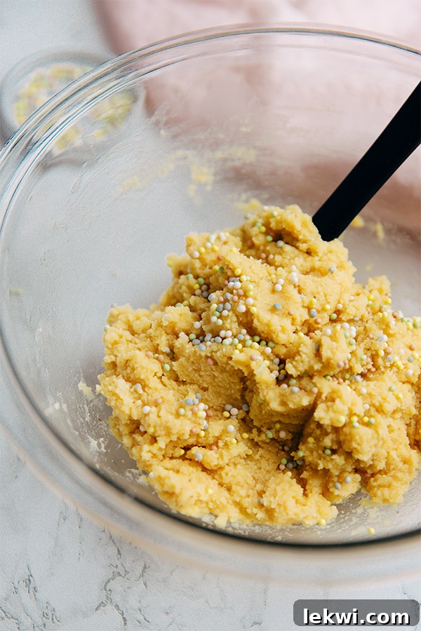 A bowl of creamy, gluten-free edible cake batter, garnished with colorful sprinkles, ready to be enjoyed as a sweet, no-bake treat.
