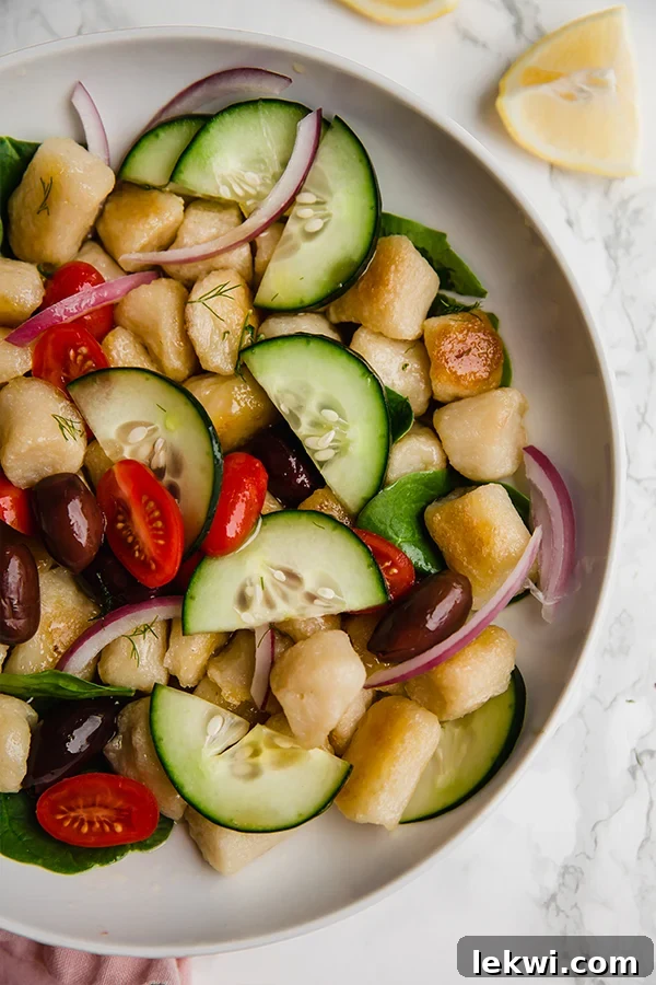 A beautifully presented white bowl filled with fresh Greek gnocchi salad, featuring the vibrant colors of vegetables and gnocchi.