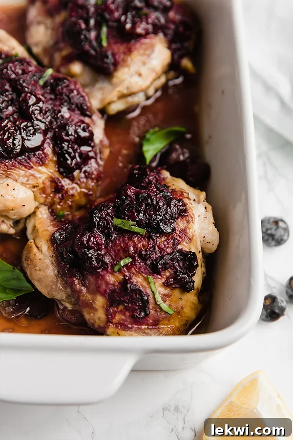A white baking dish with succulent blueberry balsamic chicken thighs, freshly cooked and ready to serve.