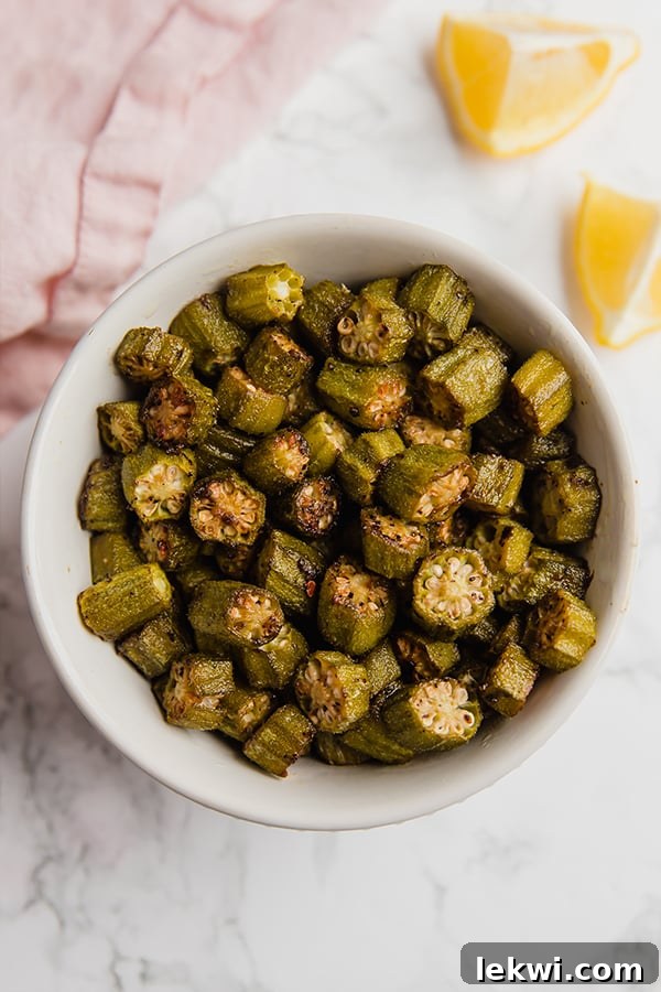 A beautifully presented white bowl of oven roasted okra, garnished and ready to serve.