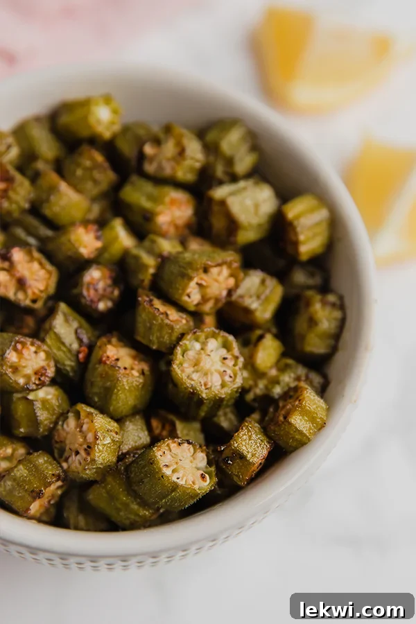 A white bowl filled with perfectly roasted okra, showcasing its vibrant green color and appealing texture.