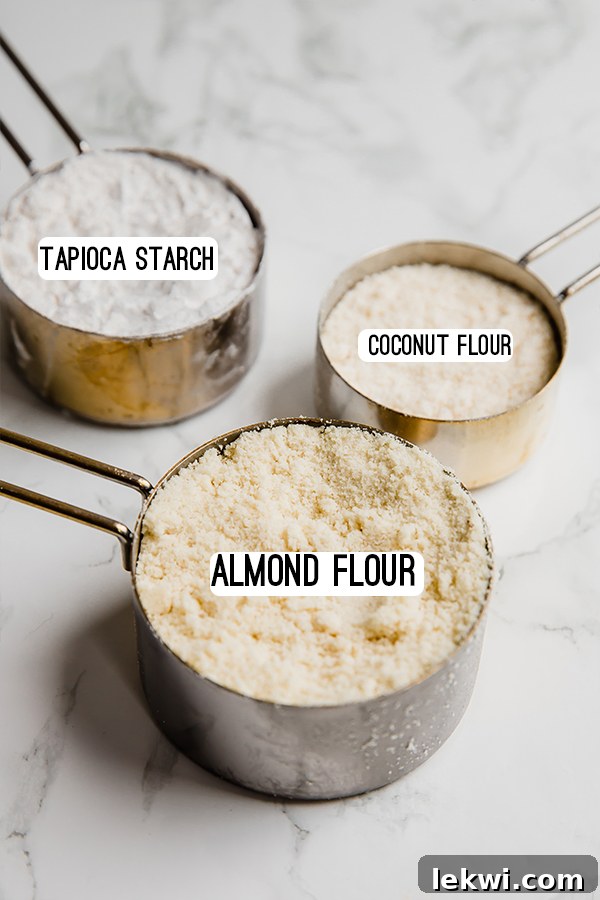 Measuring cups filled with different flours- tapioca starch, coconut flour, and almond flour.