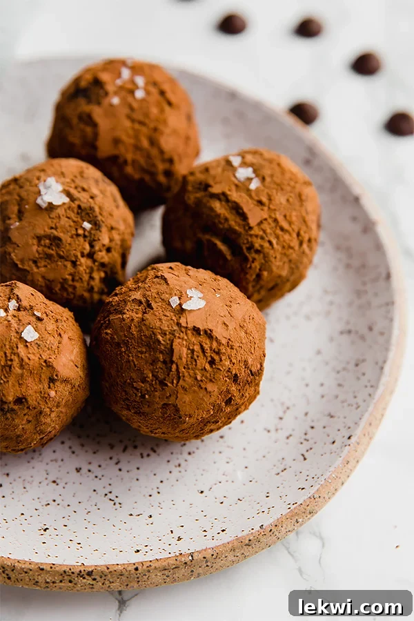 A white plate with five avocado truffles on it.