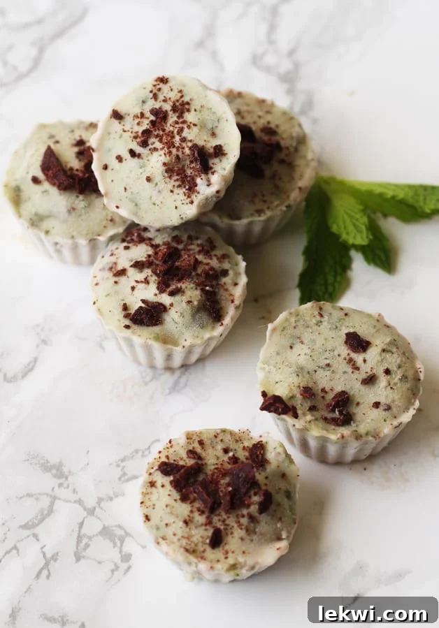 Several mint ice cream cups sitting on a counter with fresh mint.