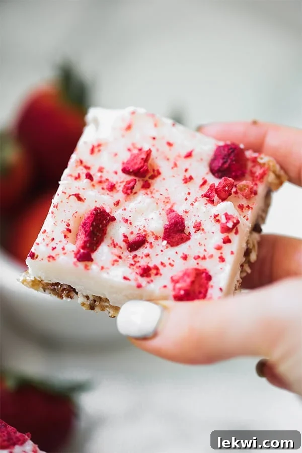 A hand holding a no bake strawberry shortcake bar in it.