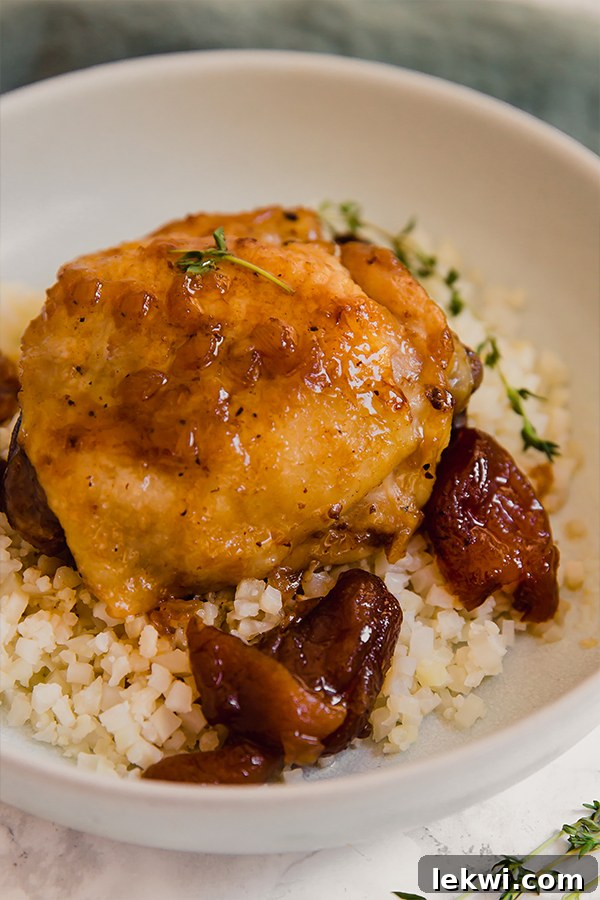 A bowl with cauliflower rice topped with a honey balsamic apricot chicken and pieces of apricot around.