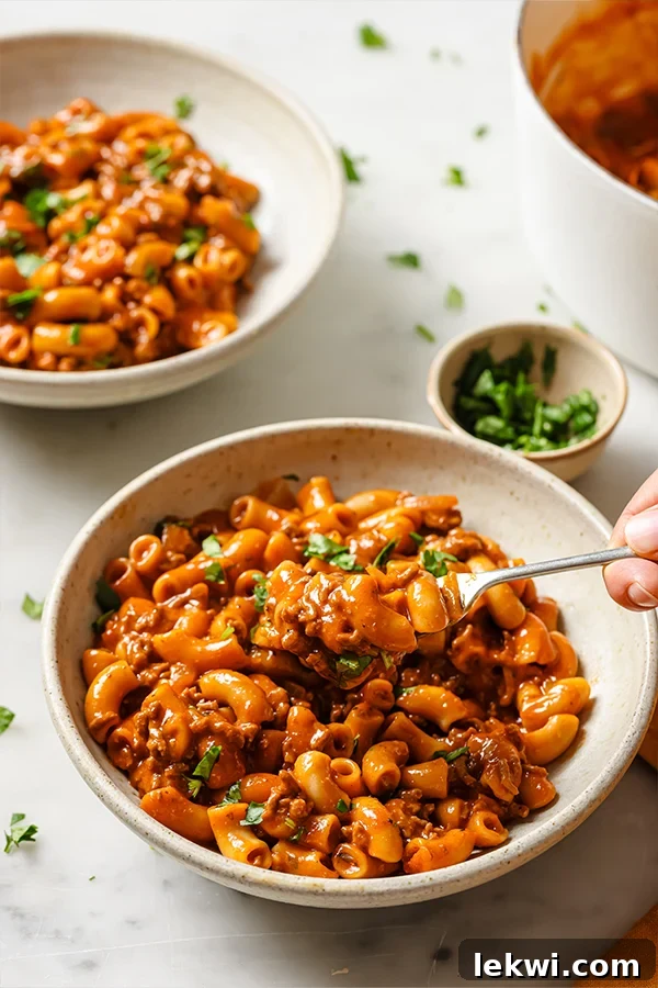 Person scooping copycat Hamburger Helper with a fork from a dish, showing its creamy texture.