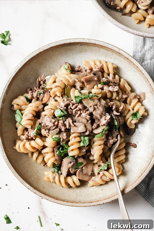 A serving of homemade beef stroganoff hamburger helper on a plate with a fork, ready to be enjoyed.