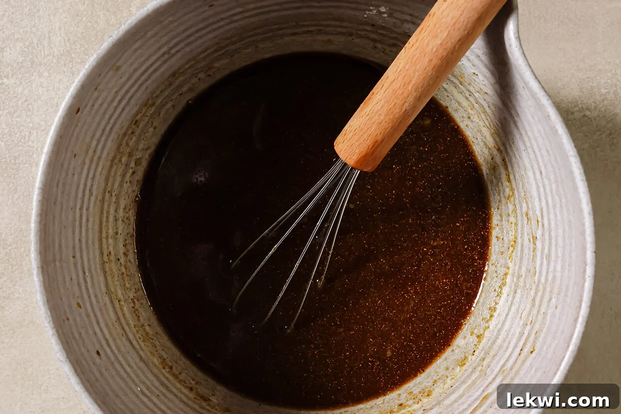 Sauce for ground beef and broccoli in a bowl with a whisk. 