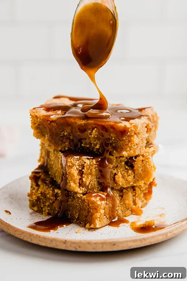 A stack of three salted caramel pumpkin blondies with caramel sauce being drizzled over it.