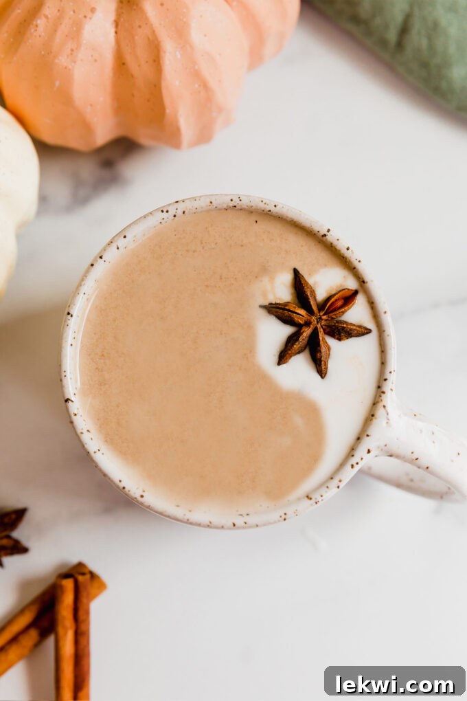 Chai pumpkin spice latte with a swirl of coconut cream and a star anise garnish, perfect for a coffee-free fall treat.
