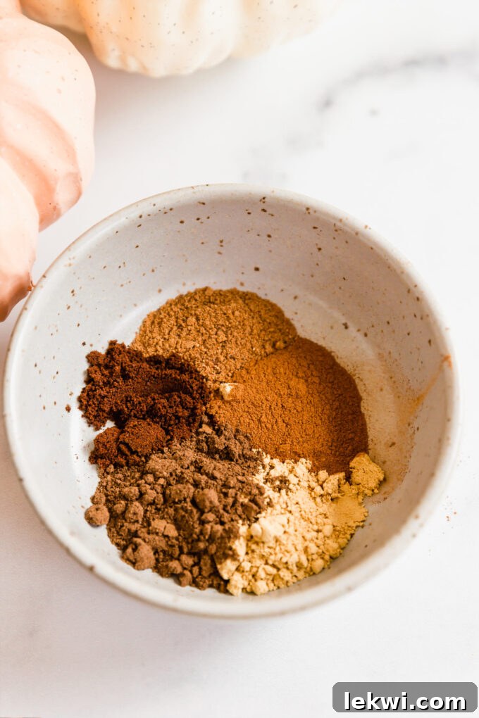 A speckled bowl filled with aromatic ground spices, ready to be mixed for a homemade chai pumpkin spice blend.