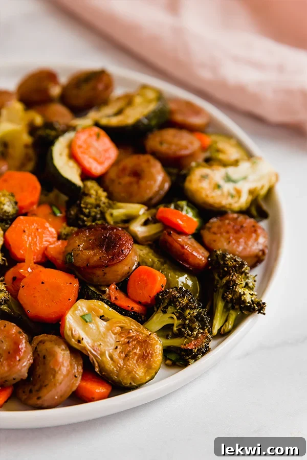 One Pan Sausage and Vegetables served on a white plate with fresh parsley.