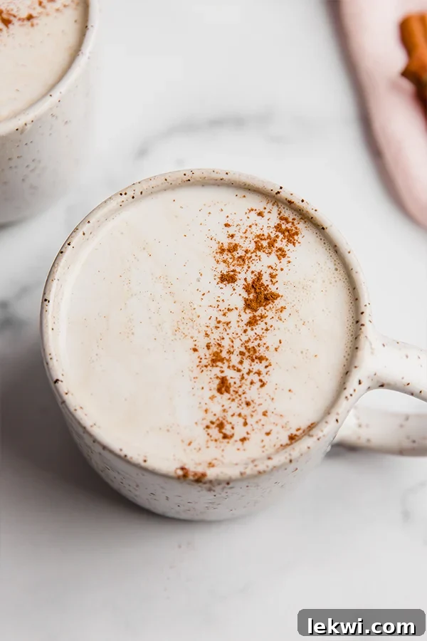 A white ceramic mug filled with a snickerdoodle latte, garnished with cinnamon powder.