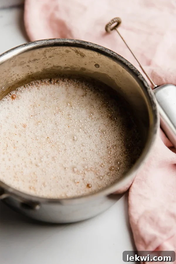 A ceramic mug filled with a snickerdoodle latte, without its final coconut cream topping, showing frothed milk.