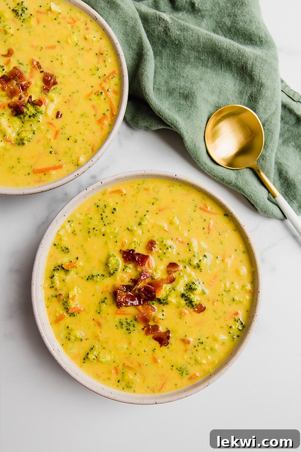 Two bowls of dairy-free broccoli cheese soup with a green napkin, showing the soup's rich texture.