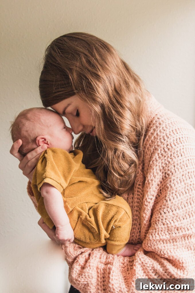 Michelle wearing a pink sweater holding her baby close to her face.