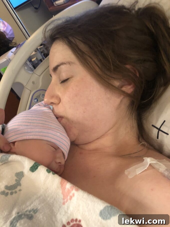 Michelle lying in a hospital bed kissing the head of her baby.