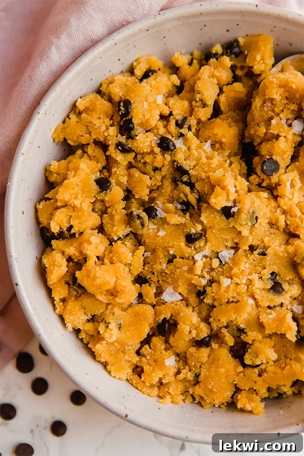 A white bowl filled with edible pumpkin chocolate chip cookie dough.