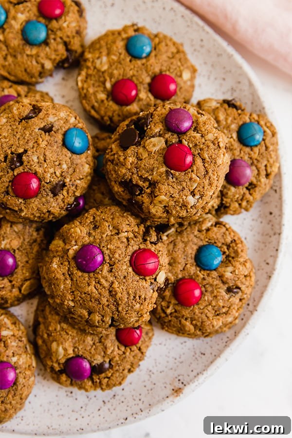 A white plate filled with perfectly baked gluten-free monster cookies, showcasing their inviting texture and colorful toppings.