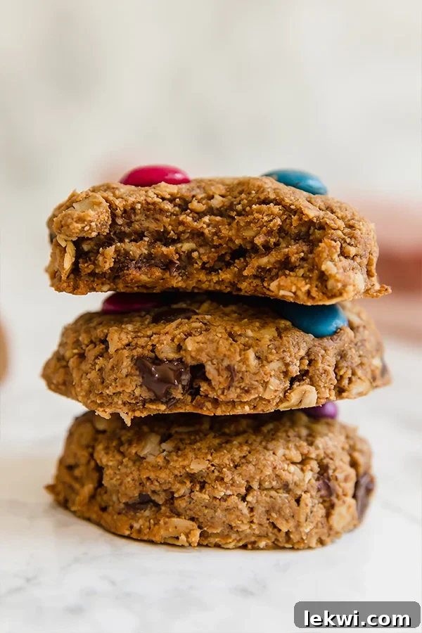 Three perfectly stacked gluten-free monster cookies, showing off their rich texture and colorful candy gems.