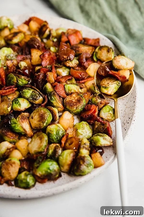 The Bacon, Date & Apple Brussels Sprout Skillet served on a white plate with a fork, emphasizing its rustic appeal and enticing texture.