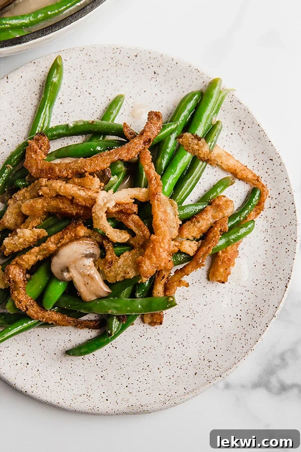 A plate with a serving of skillet green bean casserole, topped with crispy fried onions.