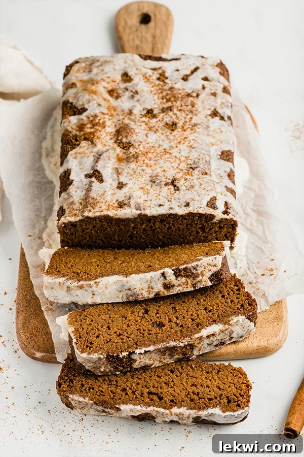 A rustic cutting board holds a full loaf of sweet potato gingerbread next to several delicious slices, showcasing its inviting texture.