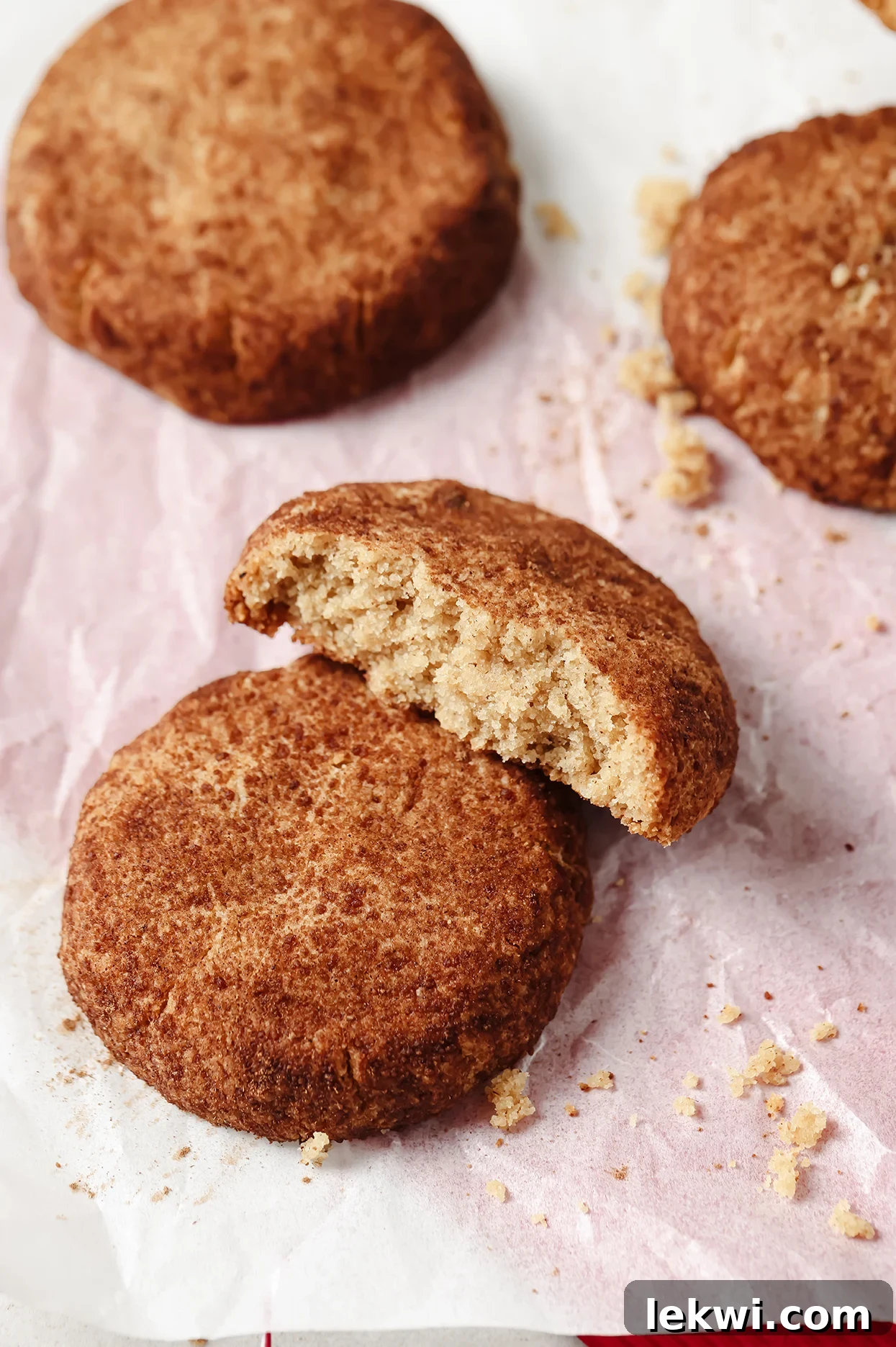 Gluten-Free Snickerdoodle Cookies on a baking sheet, with one broken in half.