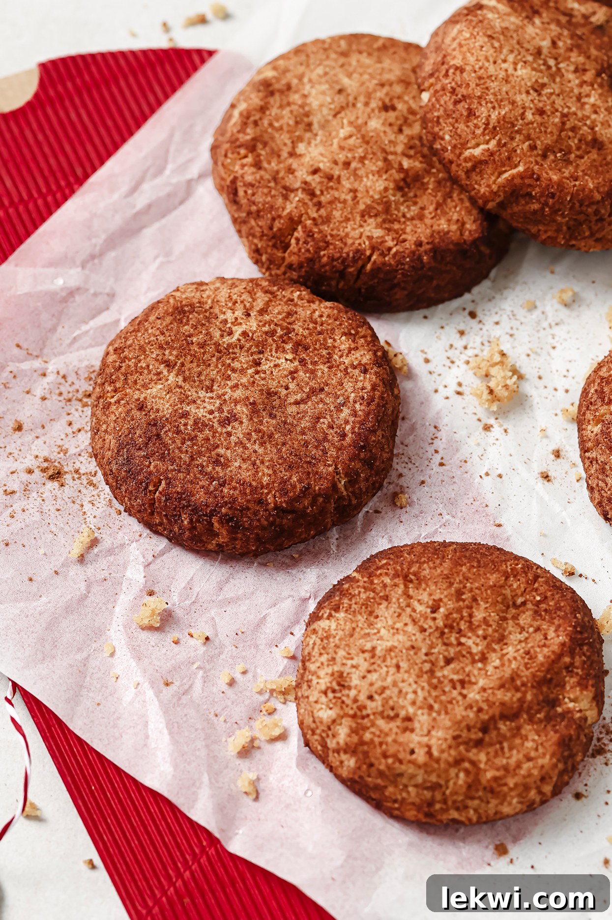 Close-up of baked snickerdoodle cookies on a tray, showing the crinkled cinnamon sugar topping and crumbs.