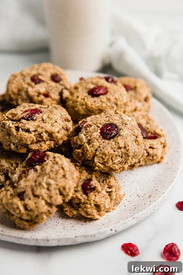 Oatmeal cranberry cookies on a platter with a glass of milk in the background.
