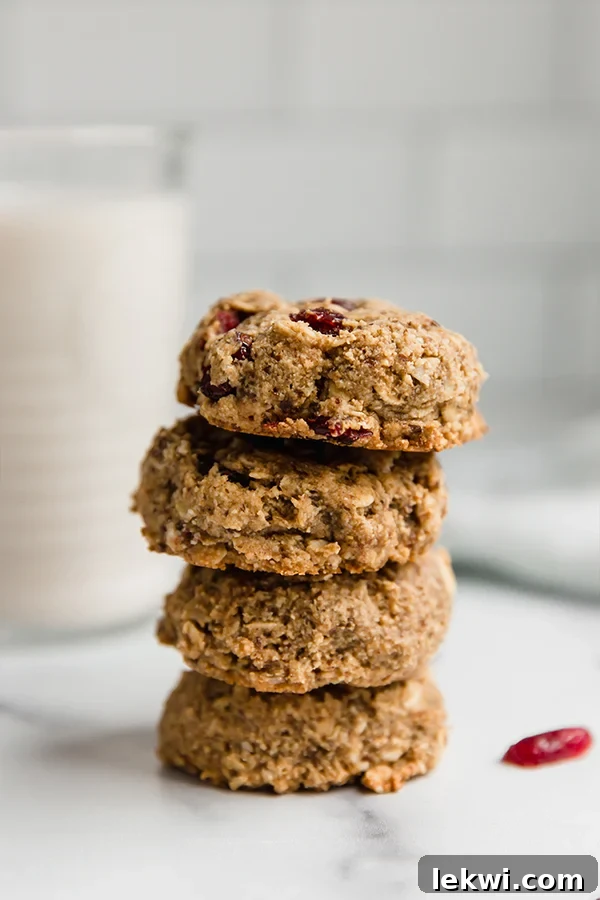 oatmeal cranberry cookies stacked on each other with glass of milk