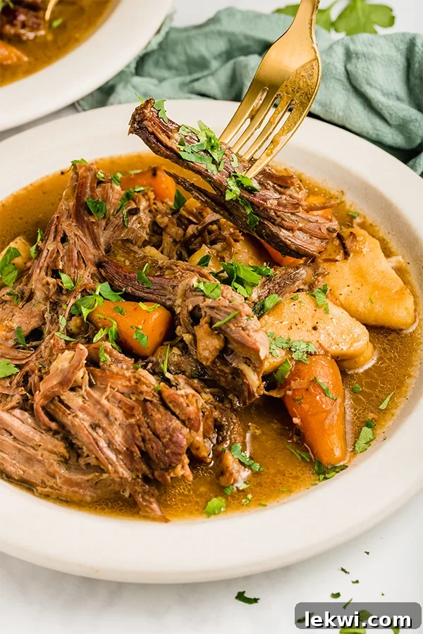 slow cooker pot roast in bowl with fork