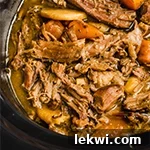 Slow cooker pot roast shredded in a slow cooker with veggies and extra broth.