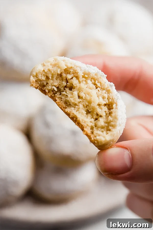 Italian wedding cookie with a bite taken out of it being held.