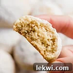 Italian wedding cookie with a bite taken out of it being held.