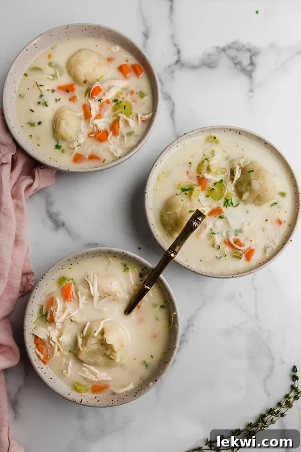Three individual bowls filled with gluten-free chicken and cauliflower dumplings soup, each with a spoon, highlighting the delicious textures.