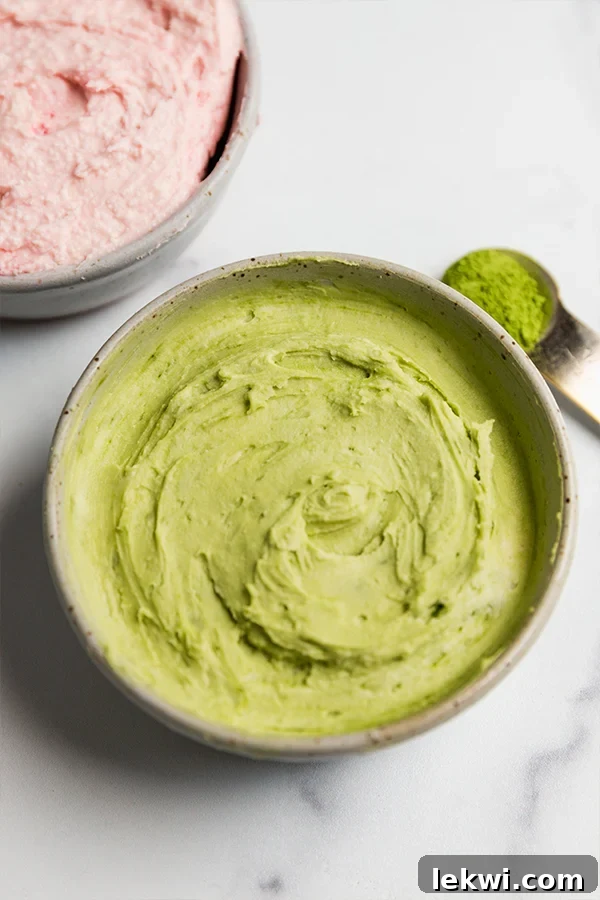 Green frosting in a bowl with matcha powder on the side.