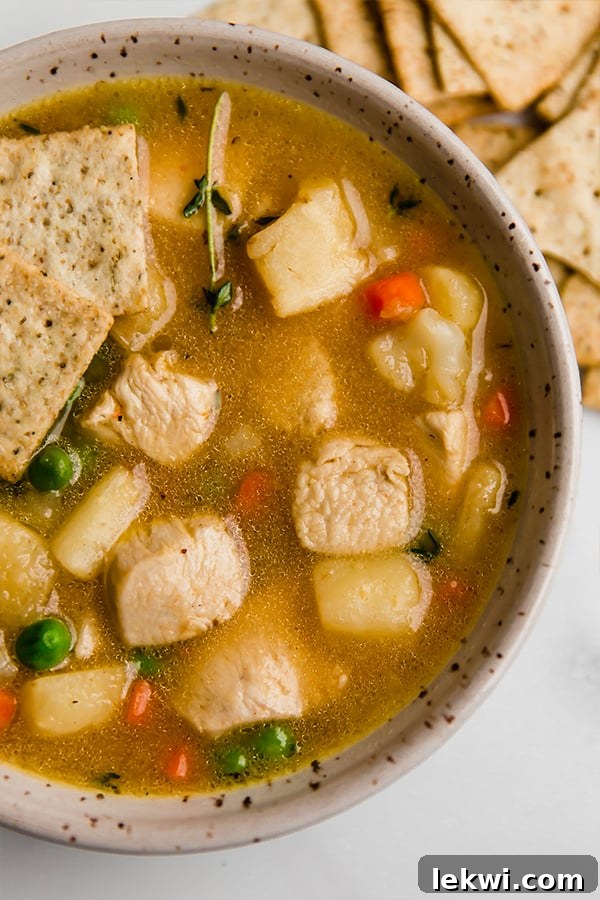 A bowl of creamy chicken pot pie soup with optional gluten-free crackers on the side, ready to be enjoyed.