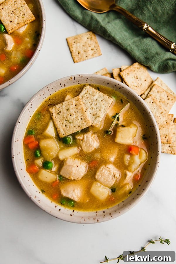 A spoonful of creamy chicken pot pie soup being lifted from a bowl, highlighting its rich texture and chunks of vegetables.