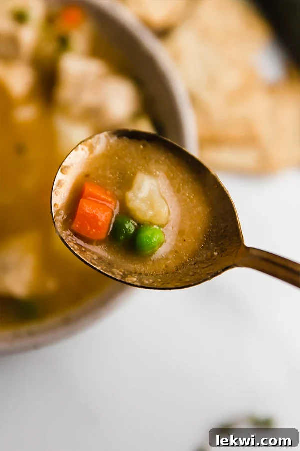 A close-up shot of chicken pot pie soup in a bowl, showing the creamy texture and chunky vegetables.