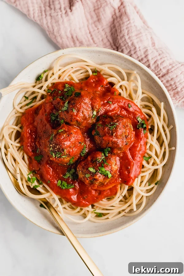 spaghetti and meatballs in a bowl with a fork